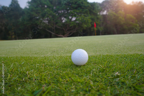 Golf ball on green in beautiful golf course at sunset background.