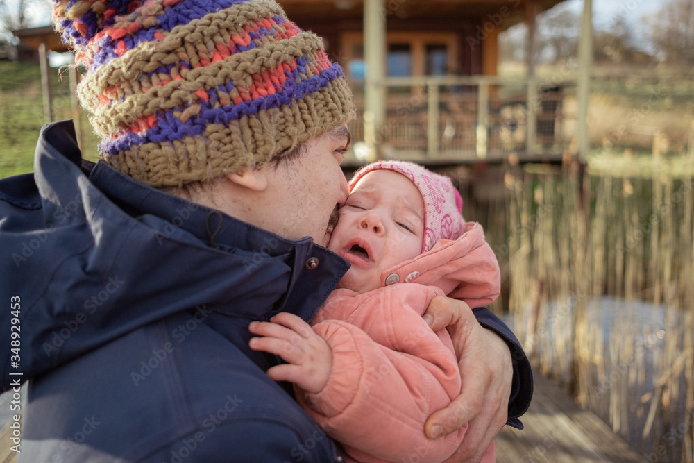 Obraz premium Father holding his little infant baby girl daughter, embracing, playing, kissing. spending time together with family outdoors. Lifestyle