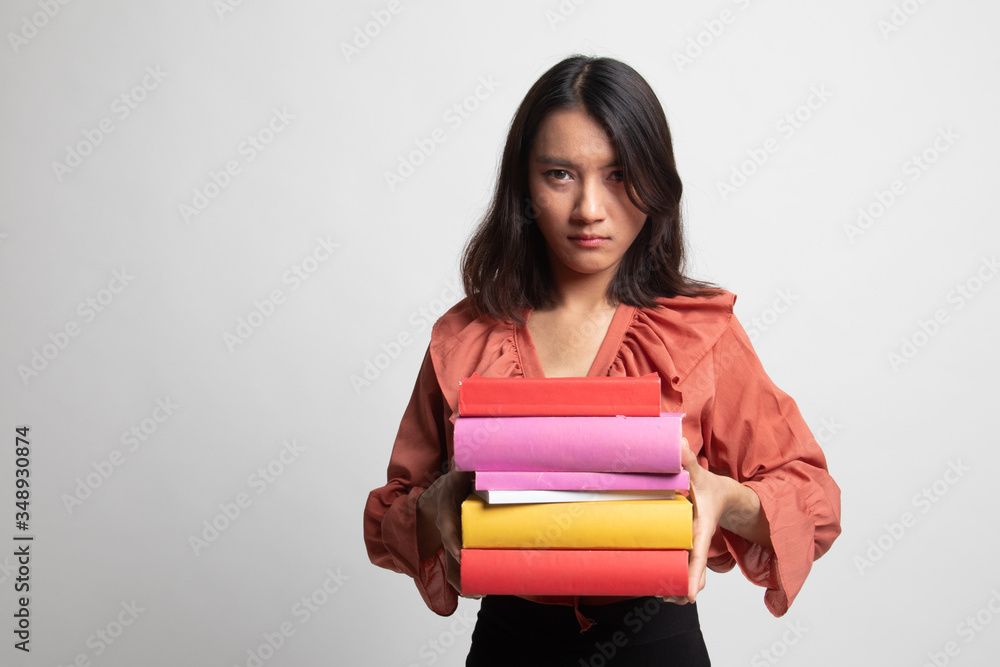 Unhappy young Asian woman studying with may books . Unhappy young Asian woman studying with may books .