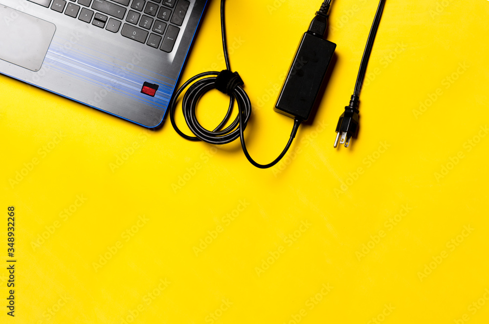 Notebook and laptop charger over yellow background. Adventure, travel and work concept. travel electric power concept. mobility and freedom concept. digital nomad concept. Topical online job.