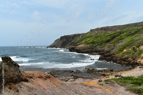 Ocean waves and mountains under a cloudy blue sky