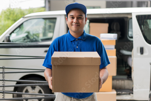 Corona Virus concept, Blue Delivery handsome asian man holding parcel cardboard box and thumbs up with protection mask and medical rubber gloves standing in front of the van © Chanakon