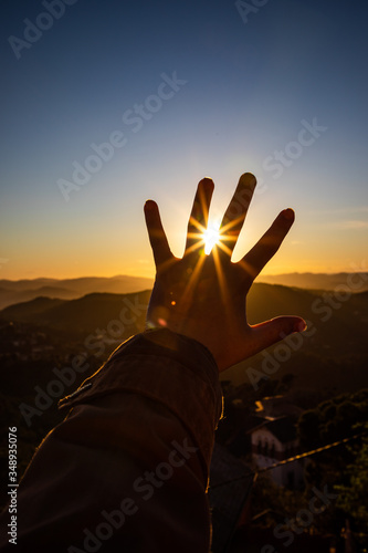 Sunset sun rays view through the fingers of a feminine open hand