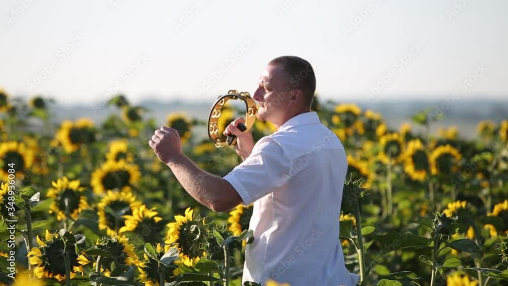 Happy dancer man playing tambourine and dancing energeticly in green summer field.
Happy dancer man playing tambourine and dancing energeticly in green summer field.