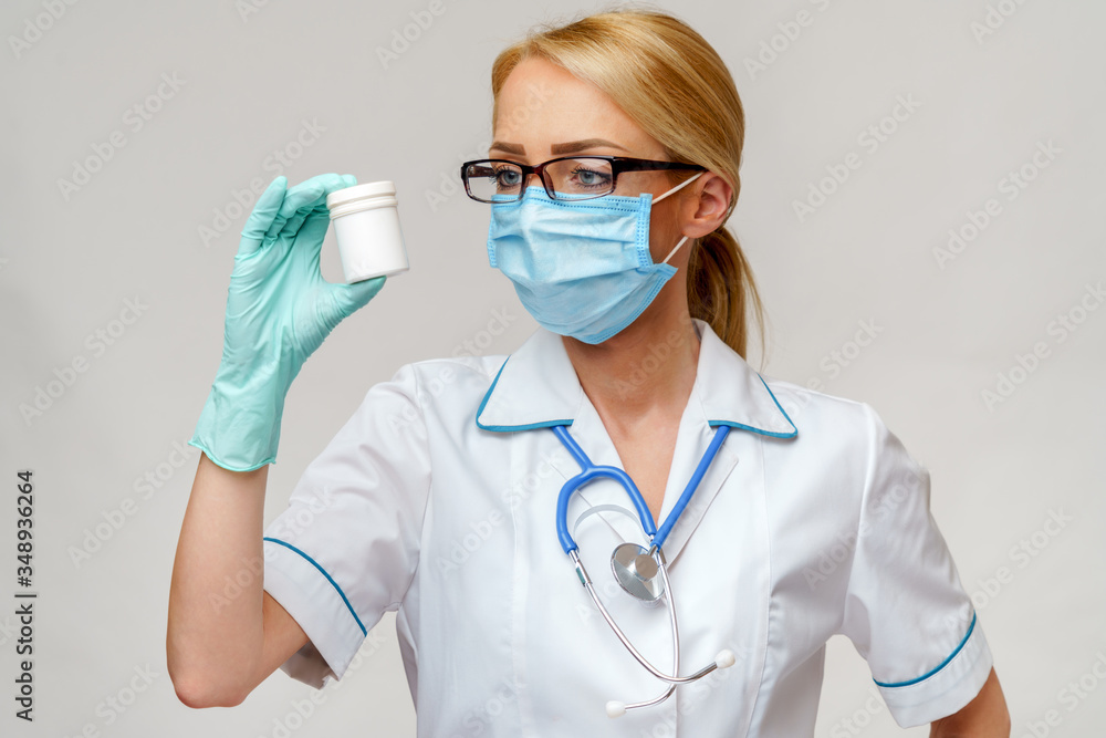 medical doctor nurse woman wearing protective mask and rubber or latex gloves - holding can of pills medical doctor nurse woman wearing protective mask and rubber or latex gloves - holding can of pills