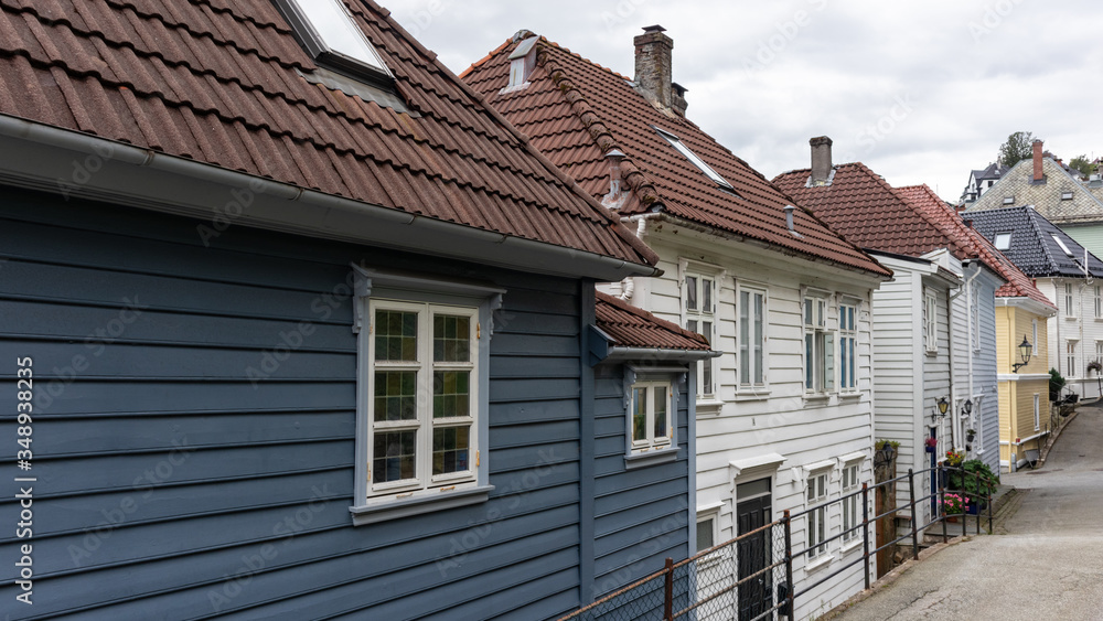 Cozy grey and white wooden old traditional houses with red roofs. Scandinavian architecture streets in Bergen, Norway. Moody cityscape