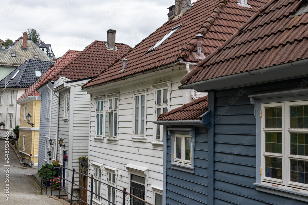 Cozy wooden old traditional scandinavian architecture houses with red tiled roofs on street in Bergen, Norway. Moody close-up cityscape