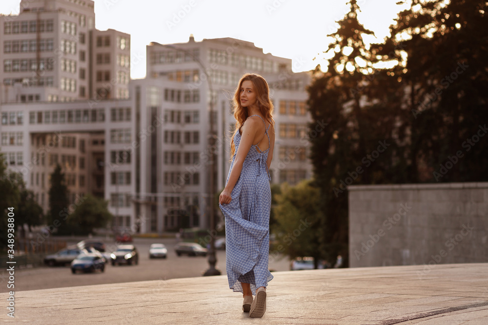 model on a summer walk in the city. evening sunset light. the girl turned and looks at the camera. blurred background