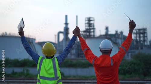 Two engineer standing at power plant site and hands up to working completed