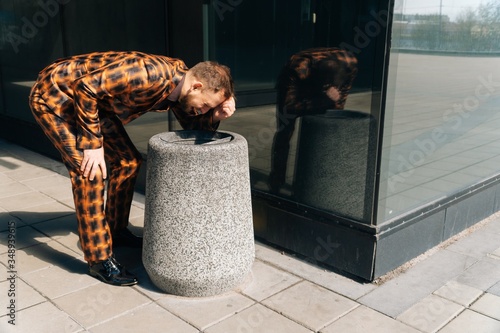 A young male manager vomits in the trash can from eating. The concept of food poisoning