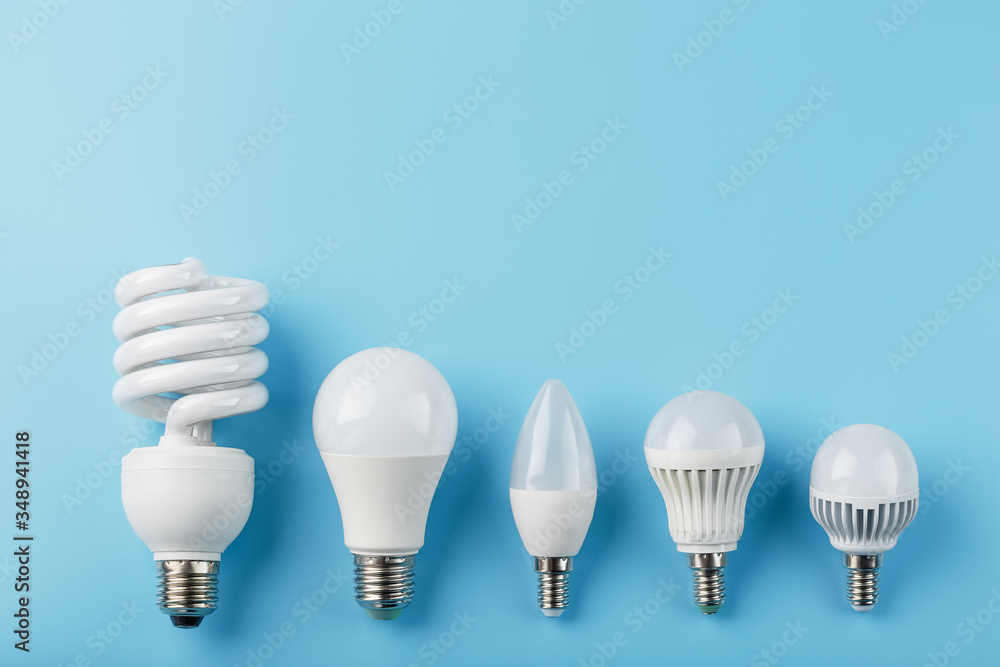 Energy-Saving light bulbs are arranged in a row on a blue background, top view. Energy-Saving light bulbs are arranged in a row on a blue background, top view.