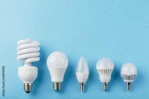 Energy-Saving light bulbs are arranged in a row on a blue background, top view. photo