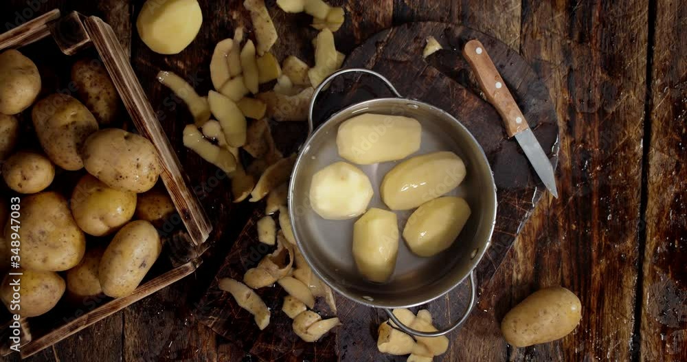 Cleaned potato falls into a pot of water with a splash. Cleaned potato falls into a pot of water with a splash.