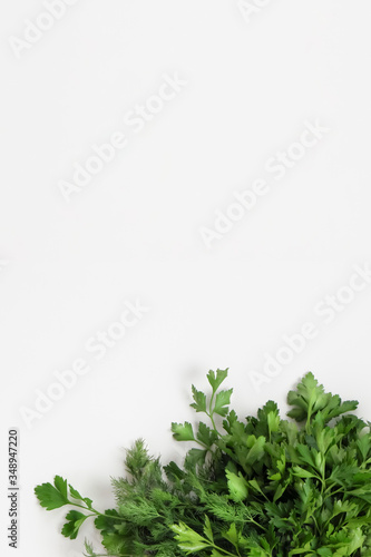 Fototapeta Naklejka Na Ścianę i Meble -  A large bunch of fresh organic green parsley, dill on a white background. Garden greens, spicy herbs, ingredients for cooking. Vertical. Close-up, top view, copy space.