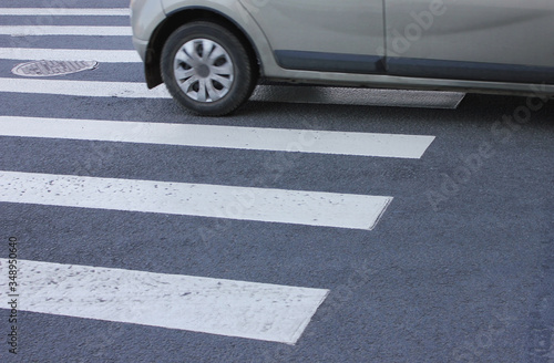 Pedestrian crossing point on city street detail. Zebra pedestrian crosswalk with single car wheels, conceptual image 