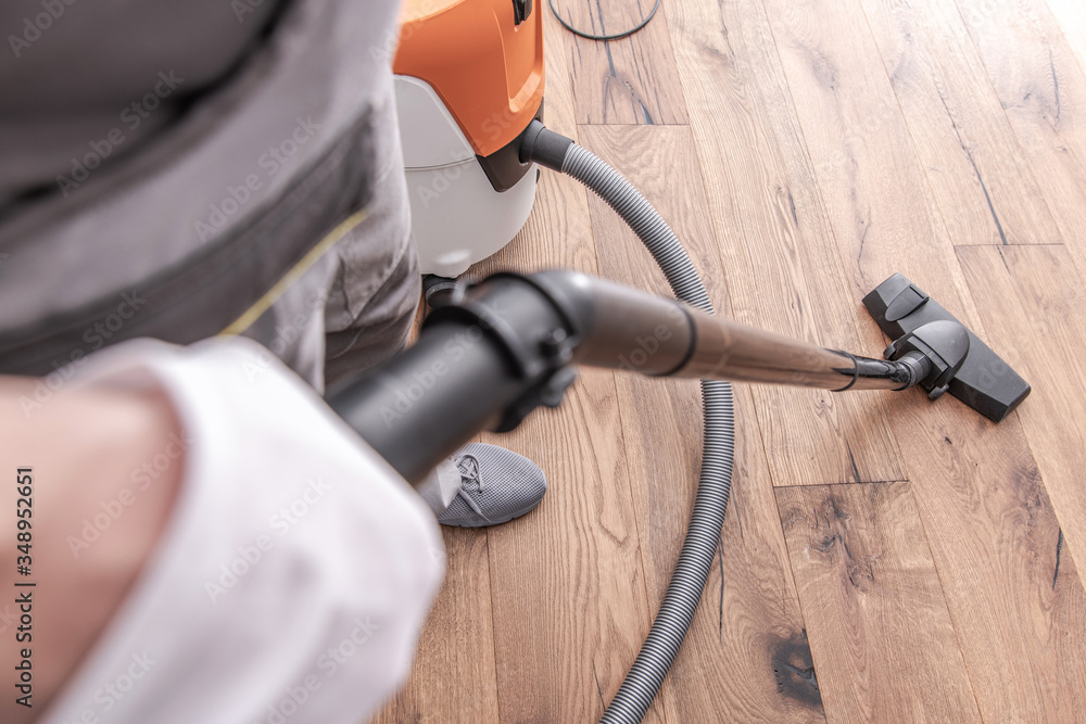 Male Worker Vacuuming Hardwood Flooring. Male Worker Vacuuming Hardwood Flooring.