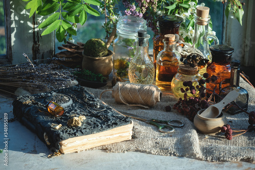 Ancient magic recipe book and magic potions in the bottle on the witch doctor table background Fototapet