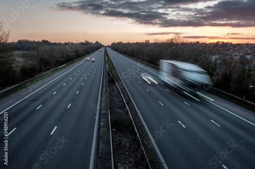 A motorway in the UK, during the Covid 19 lock down. It is early evening, during rush hour, and the motorway is almost deserted