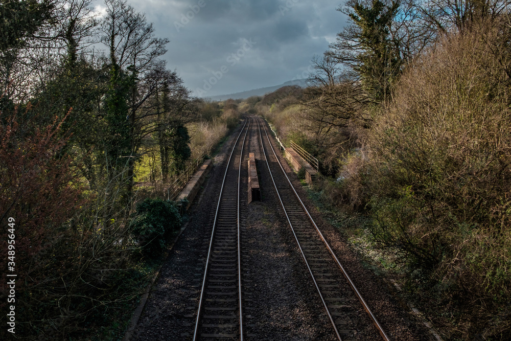 Fototapeta premium An empty railway track in the UK, under a cloudy spring sky