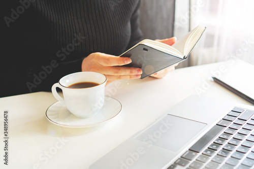 girl sits at a table, near a computer and a coffee mug