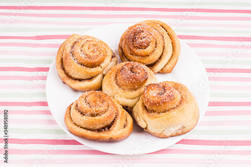 Wallpaper Mural Freshly baked homemade snail buns with sugar and cinnamon on white plate and striped tablecloth. Balanced nutrition, proteins and carbohydrates, cereals Torontodigital.ca