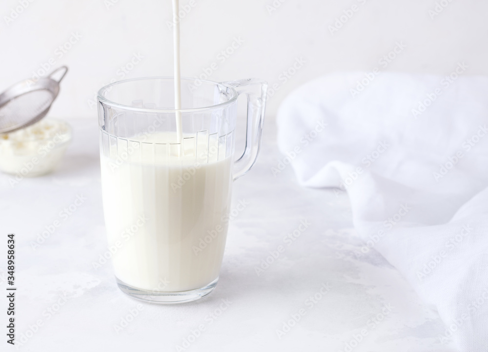 Fermented milk drink kefir is poured into a glass on a white background. Fermented milk drink kefir is poured into a glass on a white background.