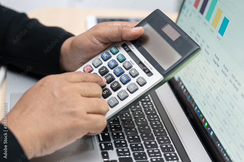 Asian accountant working and analyzing financial reports project accounting with chart graph and calculator in modern office : finance and business concept. Asian accountant working and analyzing financial reports project accounting with chart graph and calculator in modern office : finance and business concept.