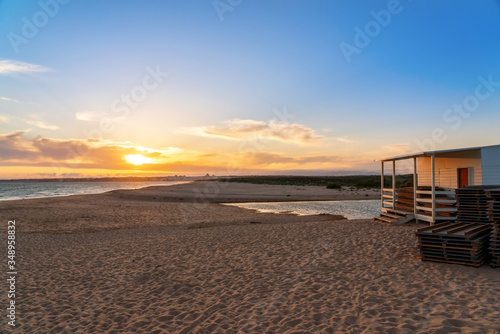 Landscape of a beautiful sunset on the ocean, with a horizon with a blue sky and a house on the sand. Portugal.