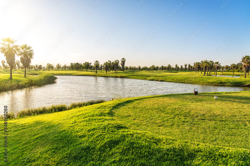 Beautiful, with green grass, golf course, with a pond, with sunny blue and clear sky. Portugal, Algarve.