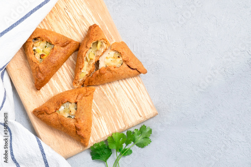 Tatar traditional triangular pastry with potatoes, onion, meat on neutral background. Image with copy space, top view
