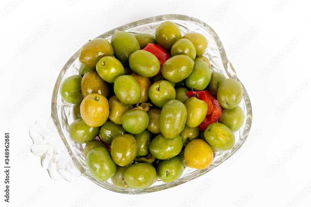 Marinated olives in small transparent bowl. On white background. Pickled green olives