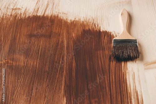 Paint brush with wooden handle and natural bristles against the background of painted brown wooden planks. Repairing concept. Top view. Copy, empty space for text photo