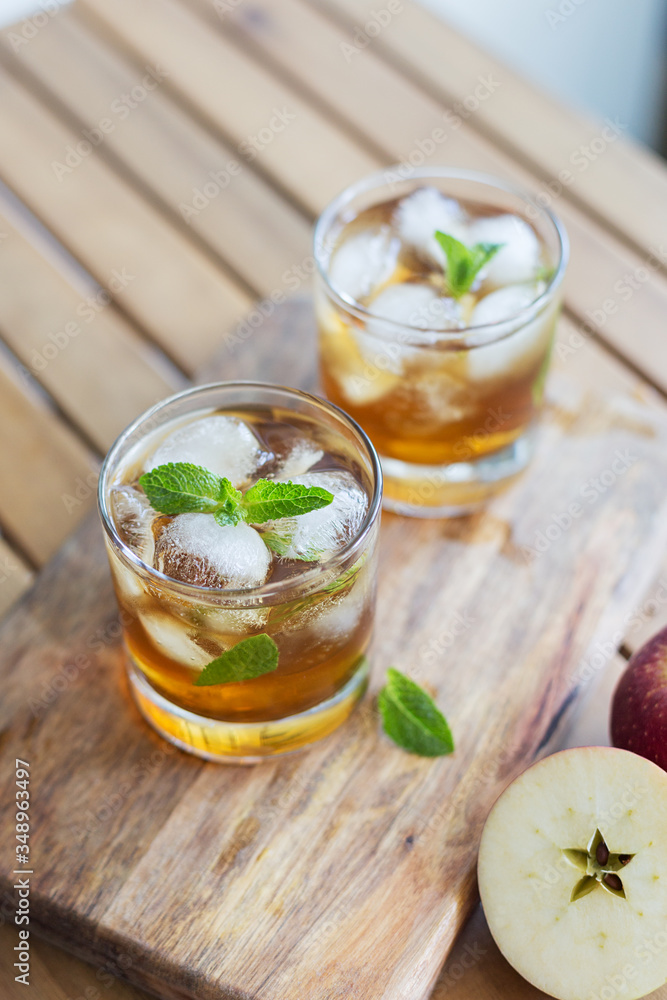 Apple juice with ice and garnish on wooden background Apple juice with ice and garnish on wooden background