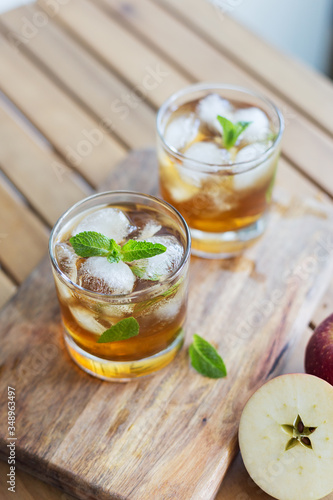 Apple juice with ice and garnish on wooden background