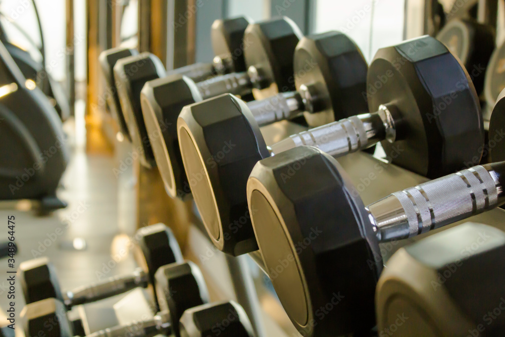 Close up dumbbells on a dumbbells rack in the gym, in the evening
