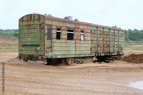 An old rusty railway car stands on the sand
