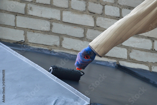 Worker paints the roof with a roller