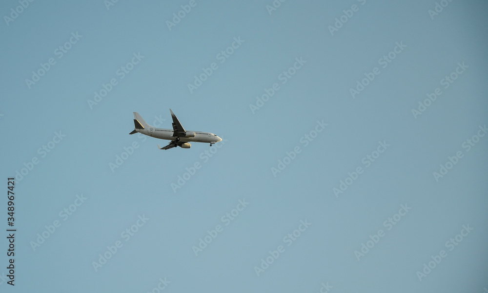 White passenger airplane flight in the blue sky landing away. Travel, transportation and wanderlust concepts.