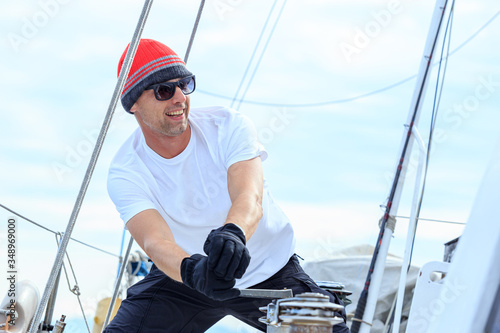 Happy sailor dressed in casual wear and sunglasses on a yacht. Norwegian fishing boat.