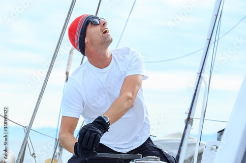 Happy sailor dressed in casual wear and sunglasses on a yacht. Norwegian fishing boat.