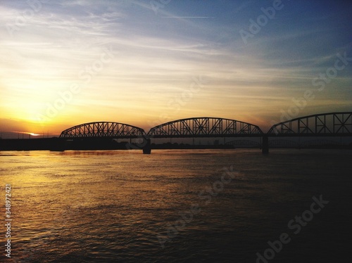 Silhouette Bridge Over River Against Sky During Sunset