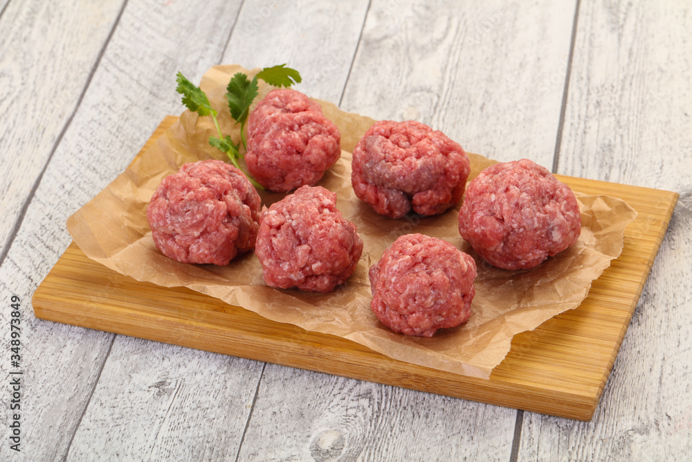 Raw meatball over wooden background Raw meatball over wooden background
