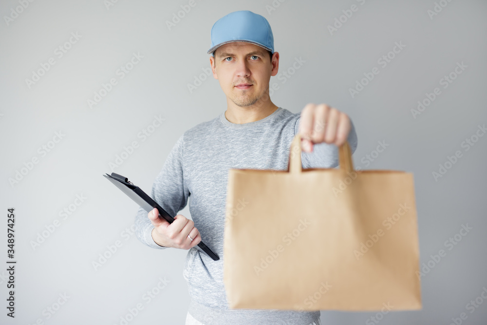 delivery concept - young delivery man holding clipboard and giving paper bag over white background delivery concept - young delivery man holding clipboard and giving paper bag over white background