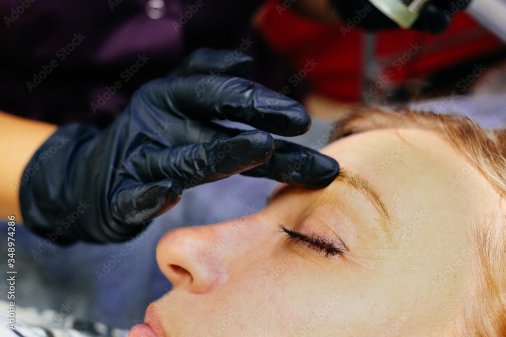 Eyebrow coloring. Woman applying brow tint with makeup brush closeup.