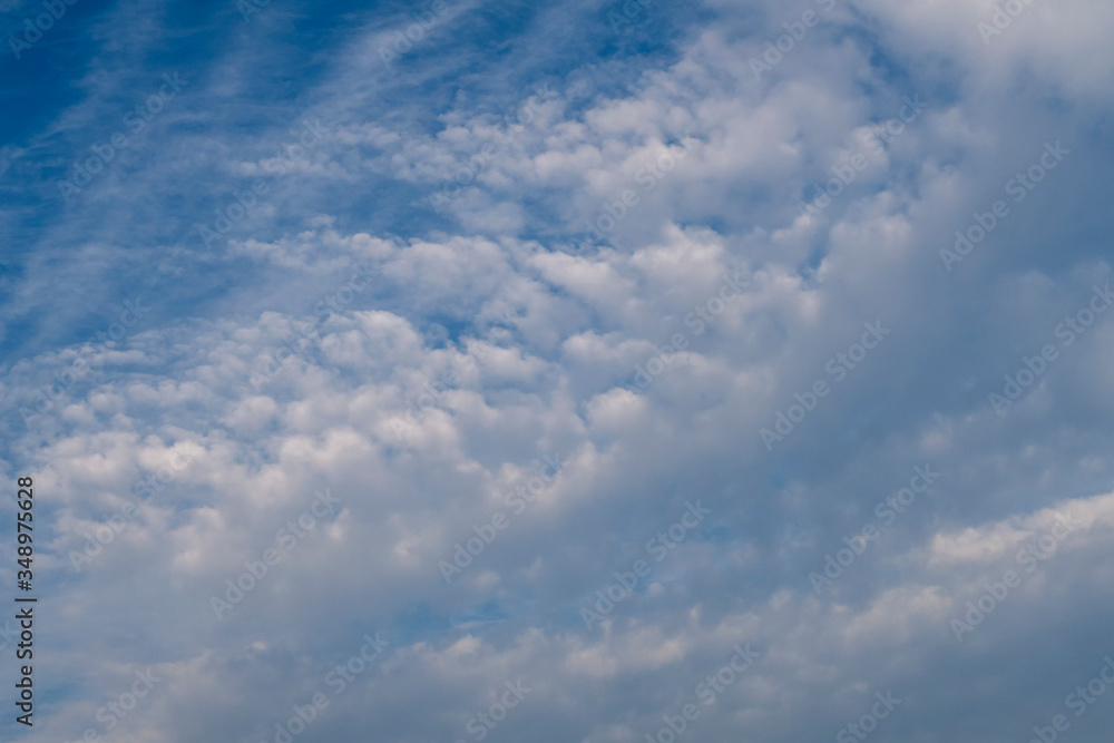 Cloudscape with white clouds against blue sky. Background image.