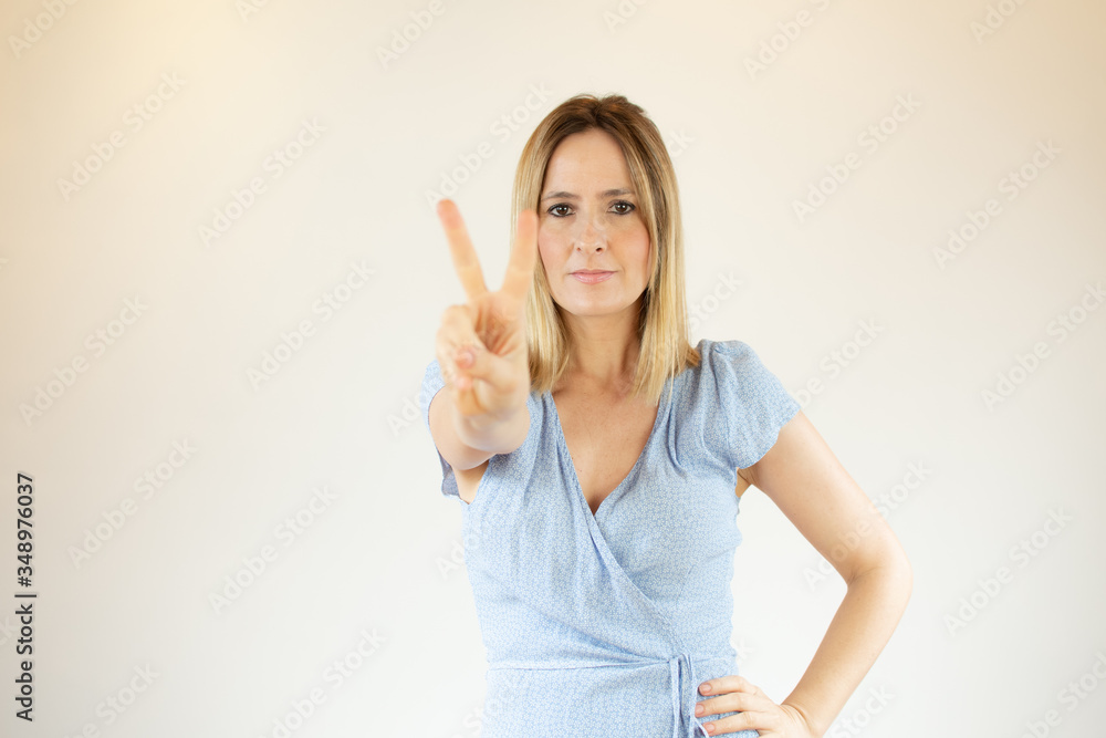 Young pretty woman wearing blue dress and making fingers up gesture Young pretty woman wearing blue dress and making fingers up gesture