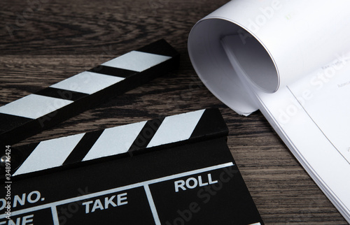 black movie clapper with a script sheets on a wooden table photo
