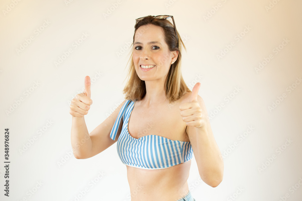 Beautiful woman wearing bikini is making fingers up gesture Beautiful woman wearing bikini is making fingers up gesture