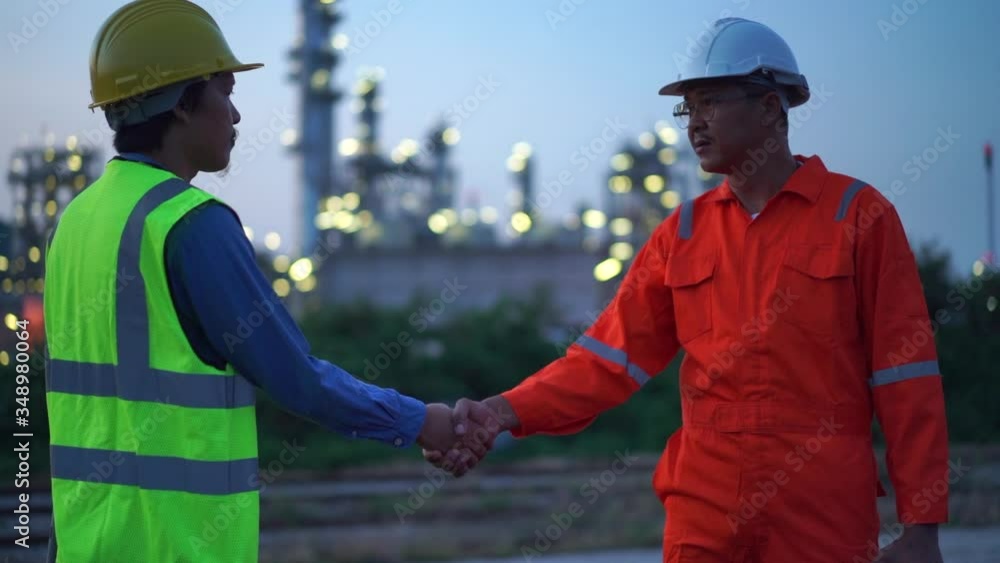 Two Asian engineer in safety suit shaking hands at night Two Asian engineer in safety suit shaking hands at night