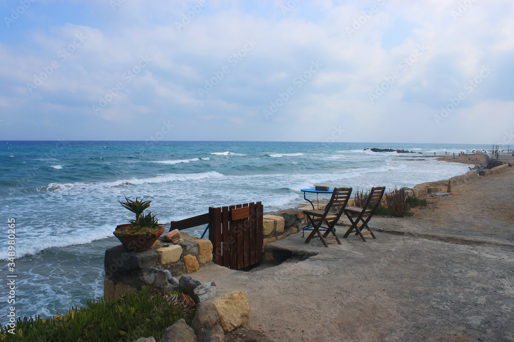 Seascape in Kokkini Hani, Crete, Greece. A table and two chairs on a deserted beach.  Scenic sea view landscape in the evening.
